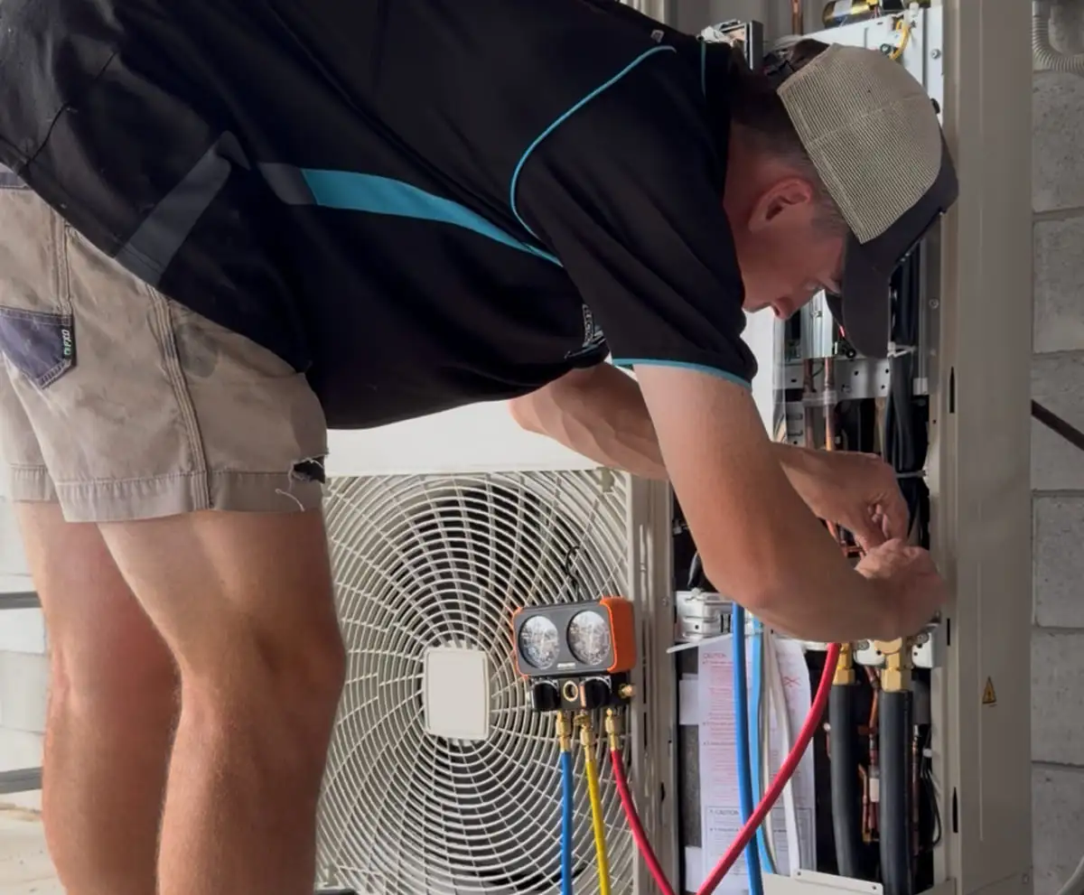 Manifold gauges connected to an outdoor air conditioning unit with the service cover off