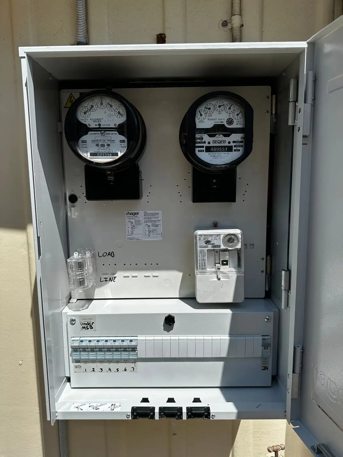 An open meter box with two meters above a new Hager board, the circuits marked up in pen