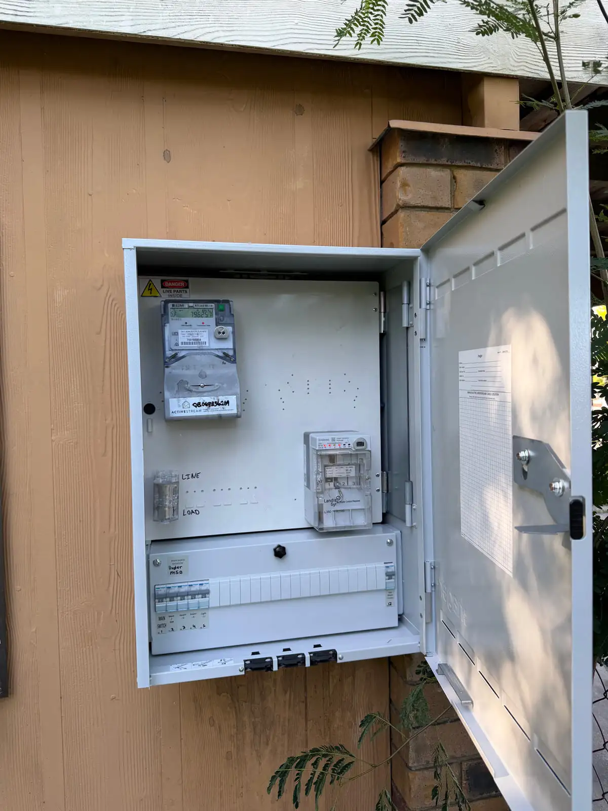A finished switchboard in its enclosure with the door open, meter above and a row of RCBOs below
